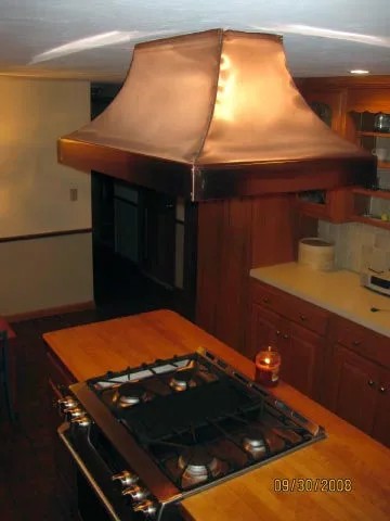Custom copper range hood above a gas cooktop